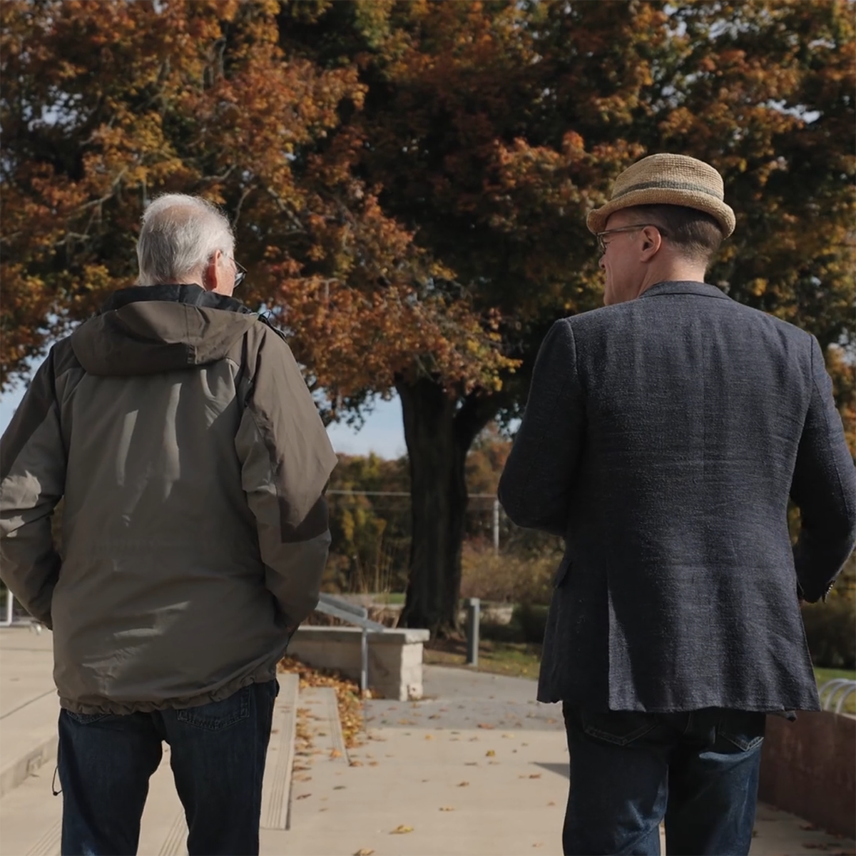 Photo of two men walking away from the camera, conversing together on 伊甸堂校园